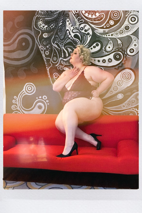 Vintage Queen Magda strikes a pose across the room on her red couch.